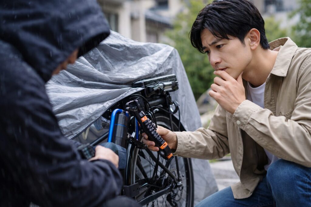 サイクルカバーをかけた電動自転車と複数ロックで防犯対策する様子